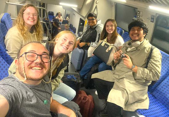 A group of students smile as they take selfie on a train.